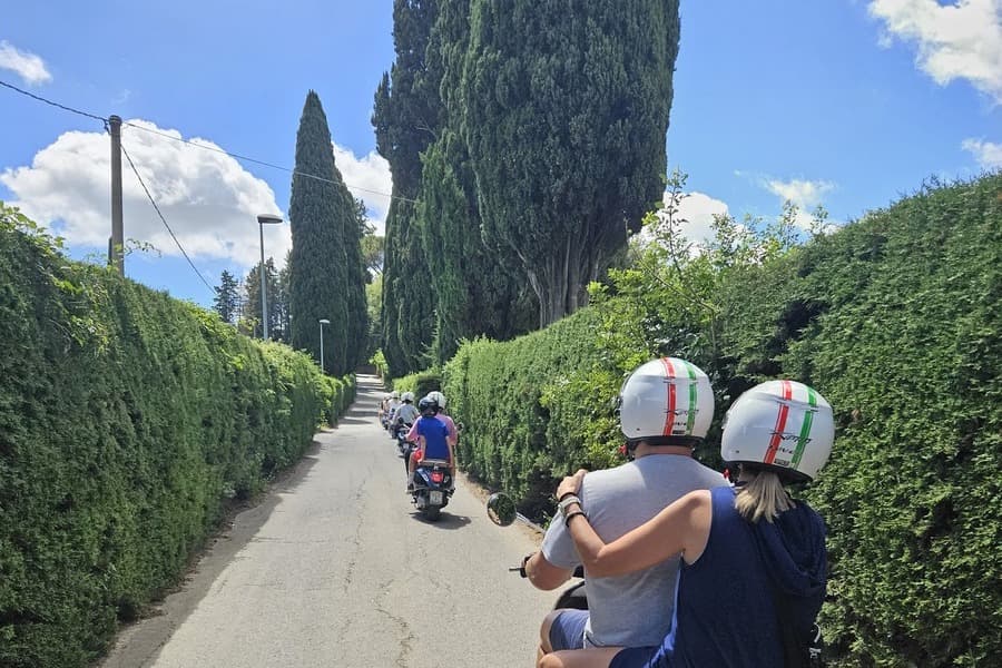 Riding the Vespa up a hill with Cypress trees